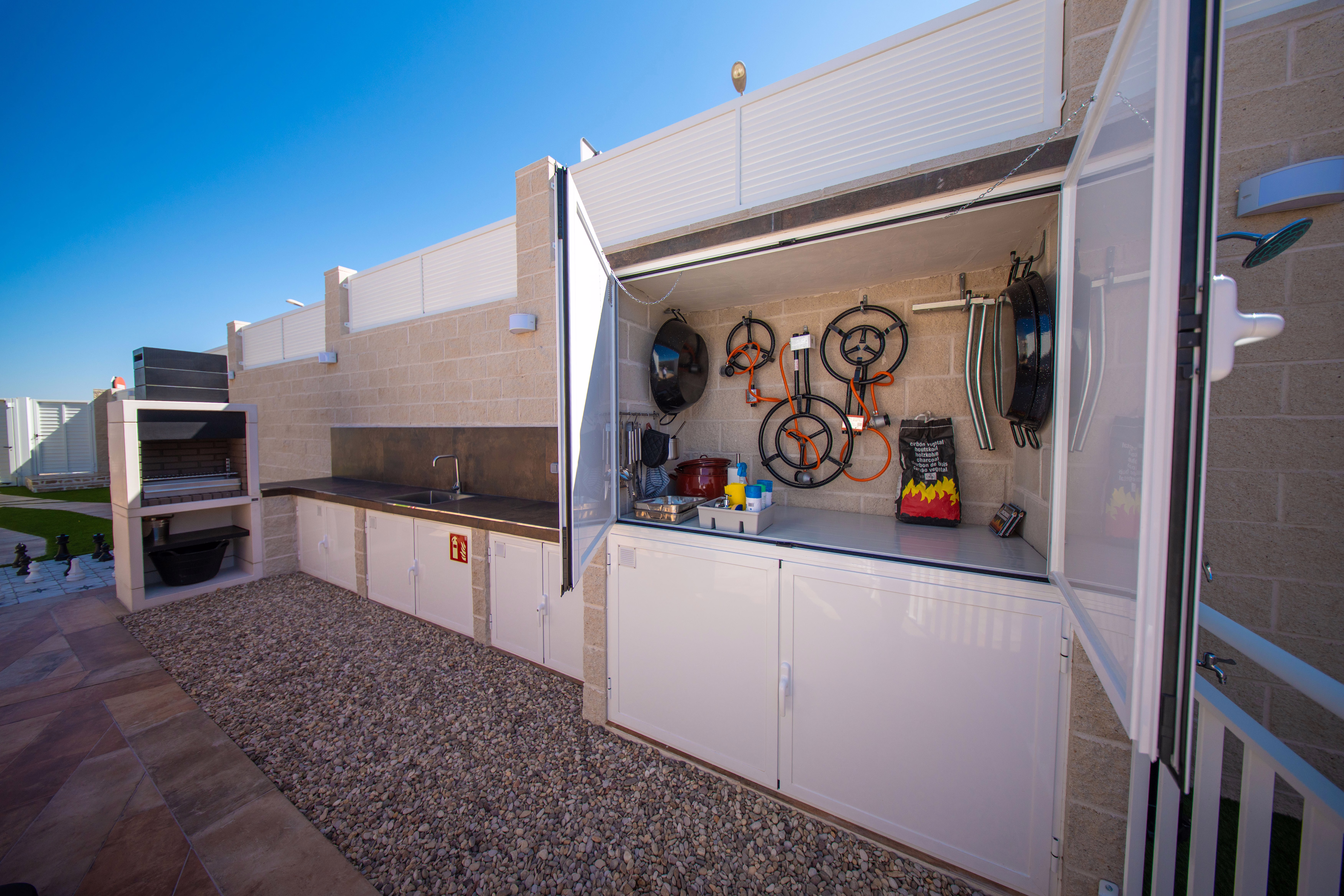 Espacio de barbacoa totalmente equipado con fregadero, encimera y armarios, ideal para cocinar al aire libre.